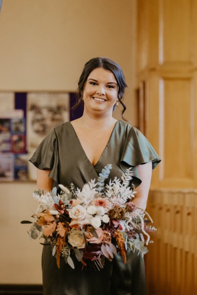 Bridesmaids smiles for the camera holding flowers