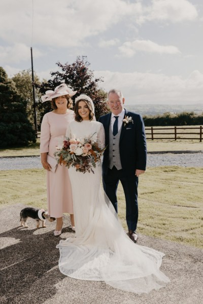 Mother father and bride standing on grass Jack Russell dog at their feet