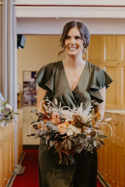 Bridesmaids smiles for the camera holding flowers