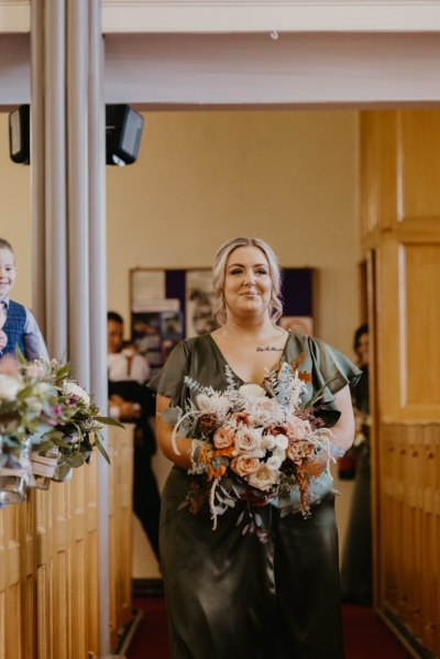 Bridesmaids smiles for the camera holding flowers