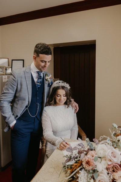 Bride and groom signing marriage certs paper