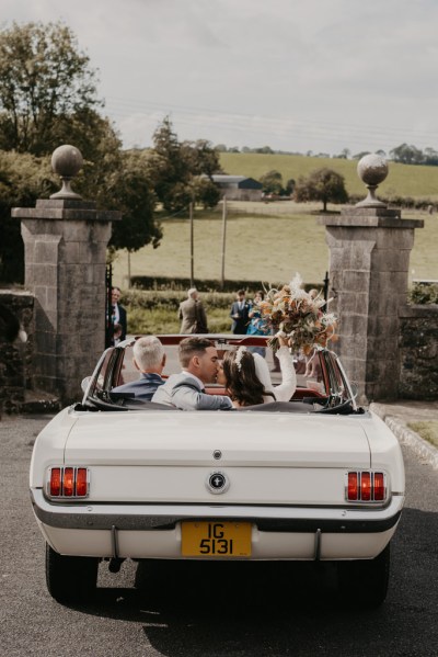 Just married wed couple bride and groom holding flowers in wedding car