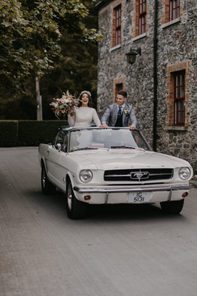 Bride and groom standing in wedding car