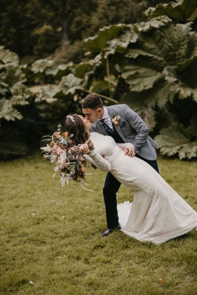 Groom tilts bride over and kisses her holding her