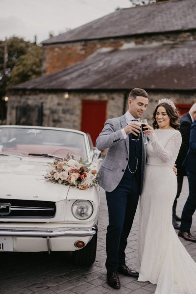 Bride and groom cheers champagne glass filled with Guinness and pint