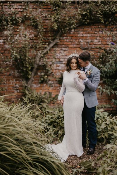 Groom takes brides hand exterior garden shot