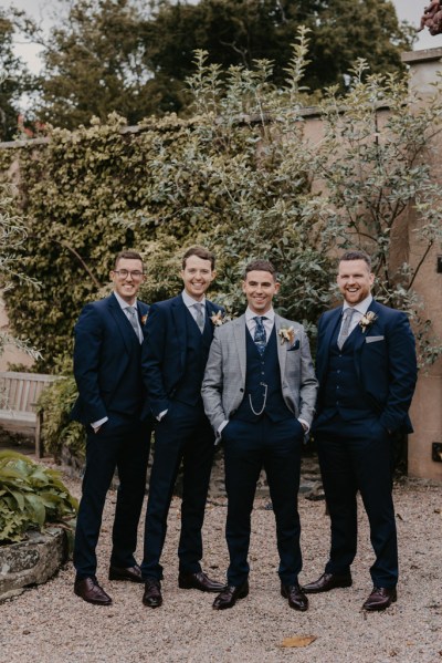 Groom and groomsmen stand in the garden