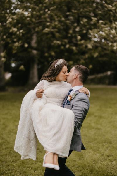 Groom picks up bride on grass