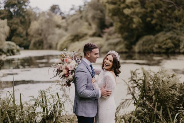 Lake in background to bride and groom standing on grass