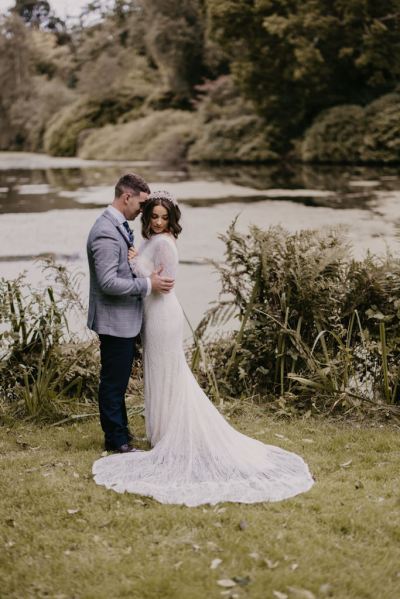 Lake in background to bride and groom standing on grass