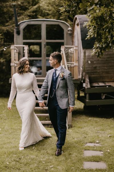 Bride and groom walk hand in hand on the grass