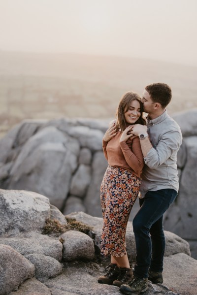 Bride and groom stand on top of a cliff/mountain