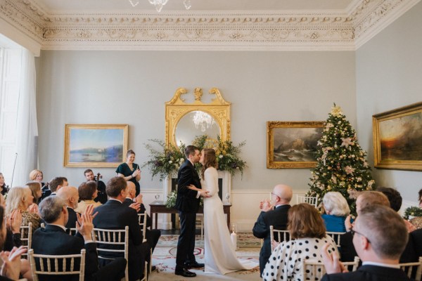 Wide shot of ceremony guests bride groom celebrant/officiant kissing