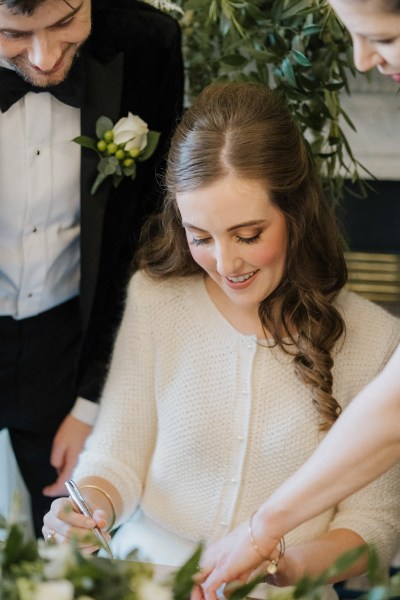 Bride signing marriage certificate with groom