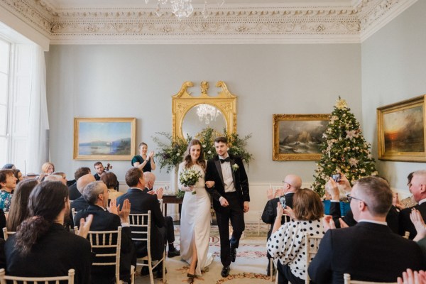 Bride and groom exit ceremony in front of guests clapping