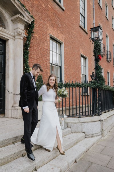 Bride and groom exit house building walking down the steps on Dublin street