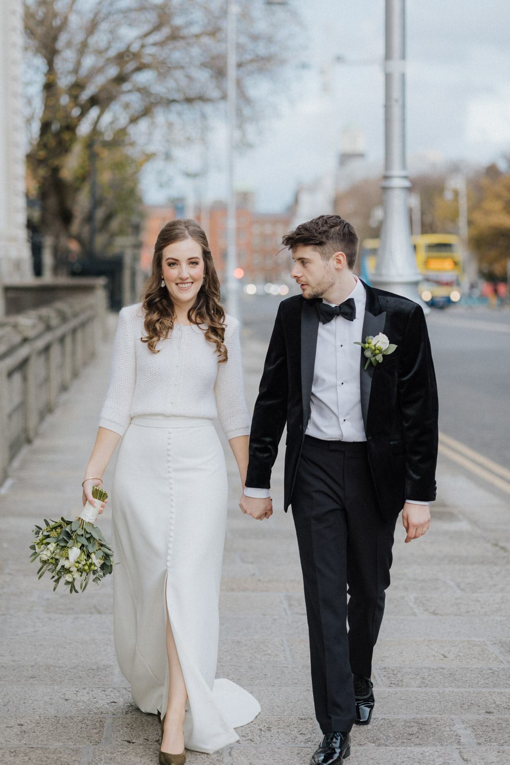 Bride and groom holding hands walking down the street