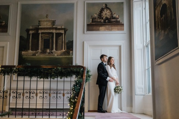 Bride and groom standing beside staircase holding each other