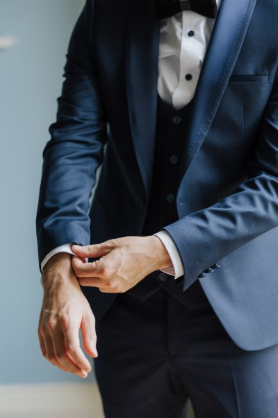 Up close detail of groom fixing suit jacket