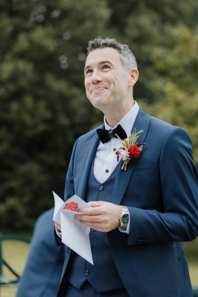 Groom close up reading card detail vows smiling