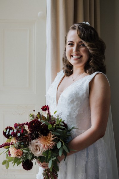 Bride stands at window holding bouquet