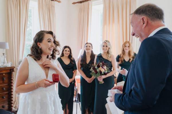 Father gives bride red jewelry box bridesmaids smile