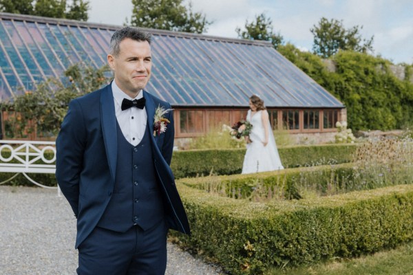 Groom awaits the bride walking in garden