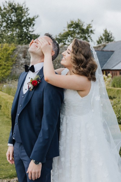 Surprise it's me bride cups hands over grooms face in garden