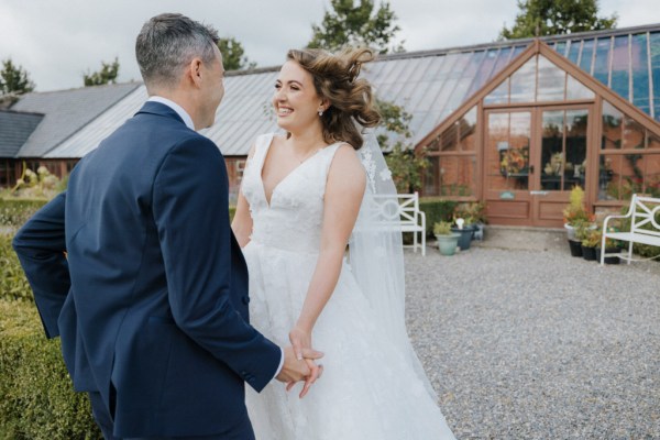 Bride and groom hand in hand outside venue