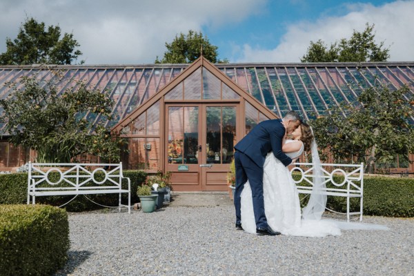 Groom kissing the bride outside of wedding venue