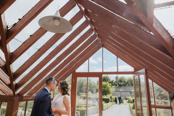 Interior conservatory setting bride and groom embrace hug