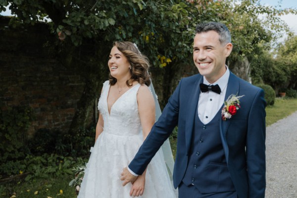 Bride and groom hand in hand holding hands in garden setting