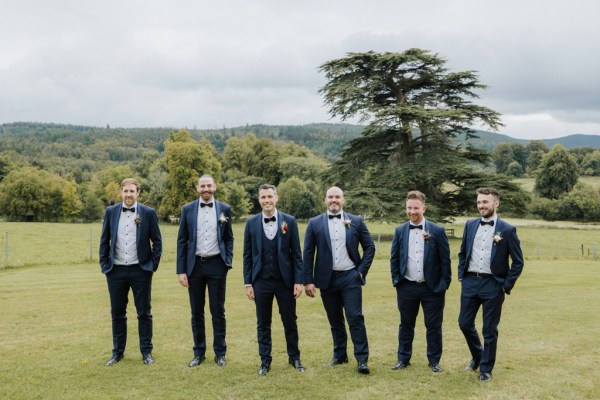 Groom and groomsmen best man walk along grass together