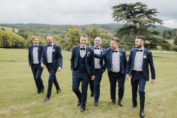 Groom and groomsmen best man walk along grass together