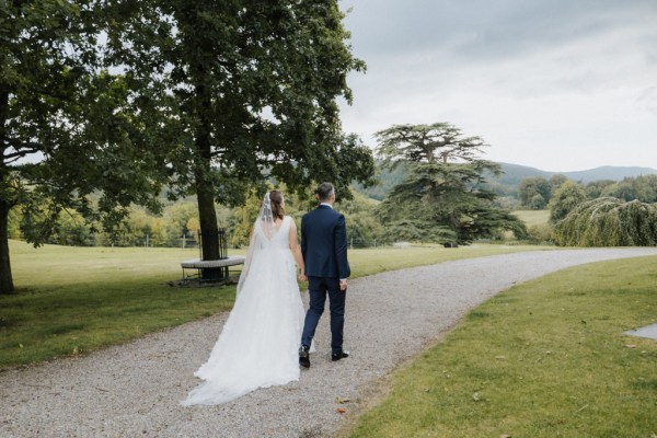 Bride and groom walking along pathway hand in hand