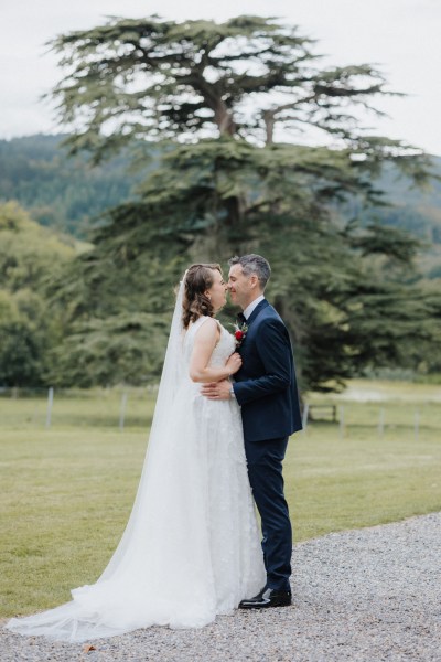 Bride and groom kissing on pathway in forest garden setting