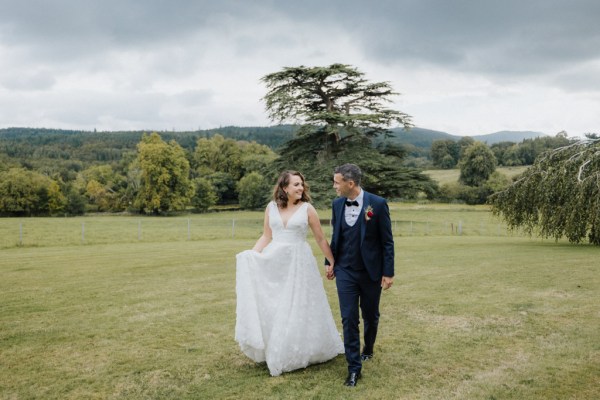 Bride and groom standing in the grass hand in hand