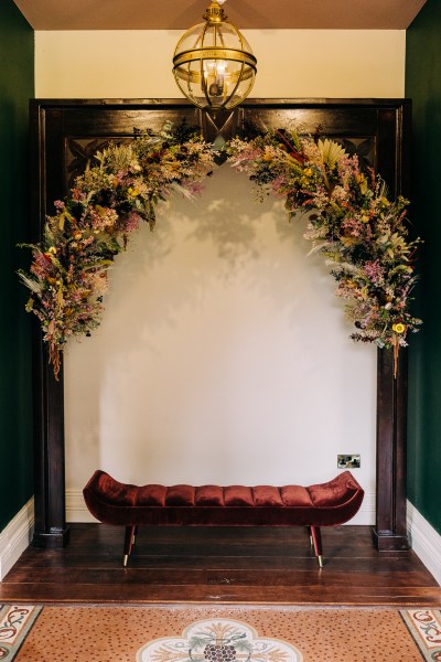 Red satin velvet couch sofa with bed of flowers/ivy above