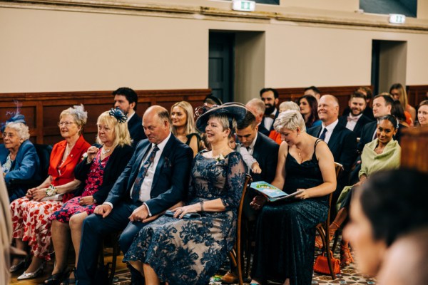 Mother and father sit in pew to church and guests seated