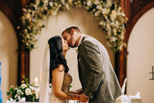 Bride and groom kiss at the alter during ceremony wedding