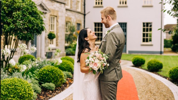 Bride and groom stand on orange carpet look at each other