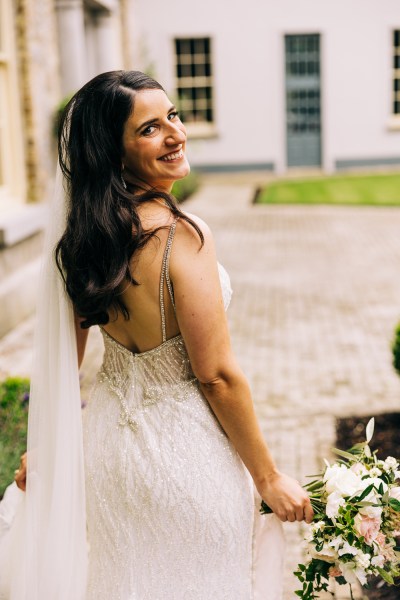 Bride looks over her shoulder in garden