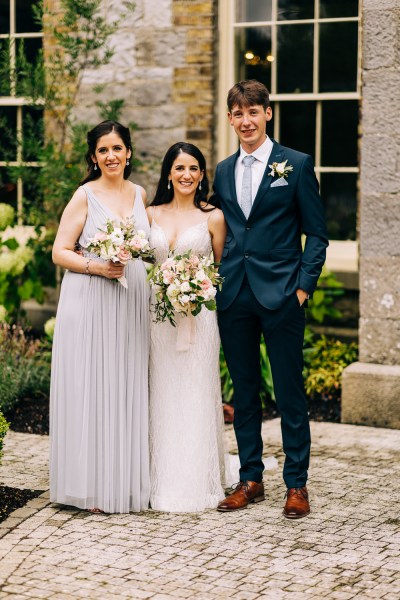 Bride and bridesmaid holding bouquet flowers and male friend/brother