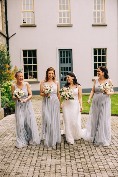 Bride and bridesmaids walk in courtyard