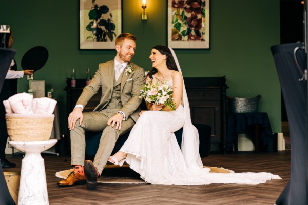 Bride and groom laugh and smile at each other as they are seated