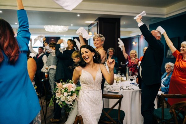 Bride and groom walk into dining room ballroom to guests clapping