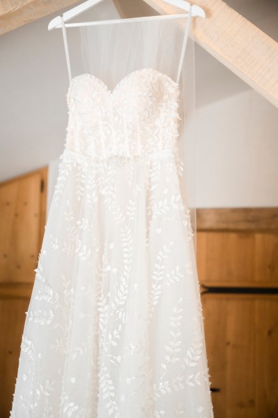 White bridal patterned gown hanging up in bedroom bridal gown