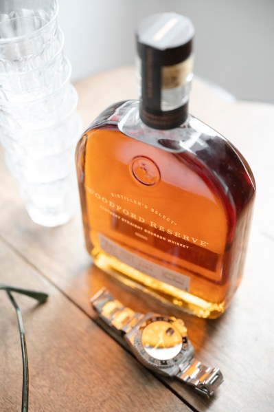 Perfume bottle on table alongside watch