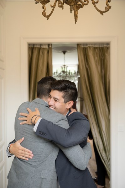 Groom and groomsman hug embrace smiling emotional