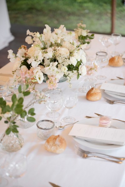 Close up of white roses bouquet flowers on table alongside cutlery plates and bread